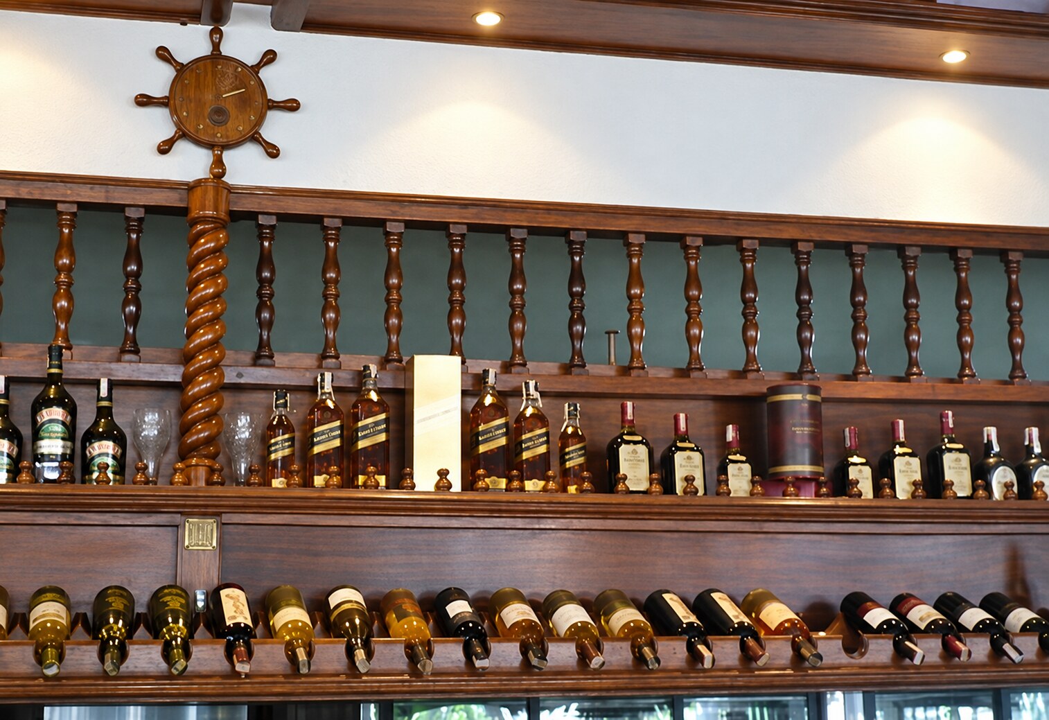 Bar comercial de madera con balaustres, columna helicoidal y exposición de botellas